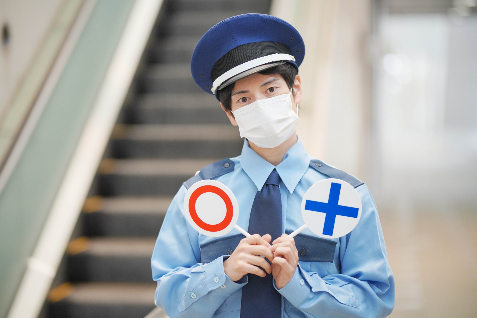 丸と罰のマークを持って疑問を感じる警備員