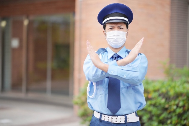 バツのポーズをする男性警備員